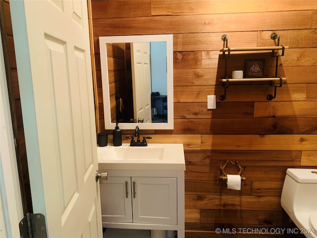 bathroom with wood walls, vanity, and toilet