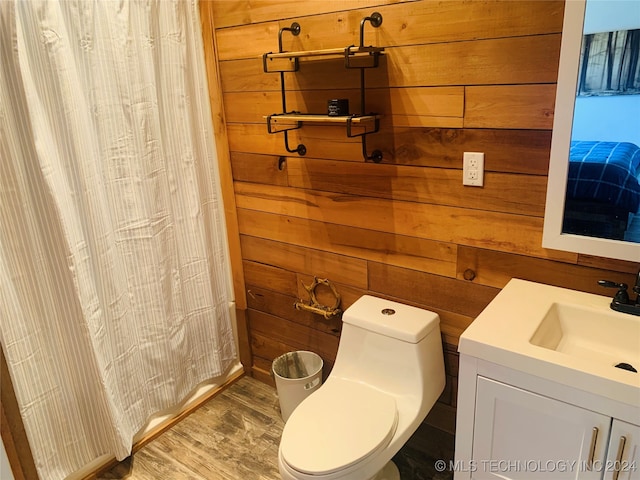 bathroom featuring wooden walls, toilet, vanity, and wood-type flooring