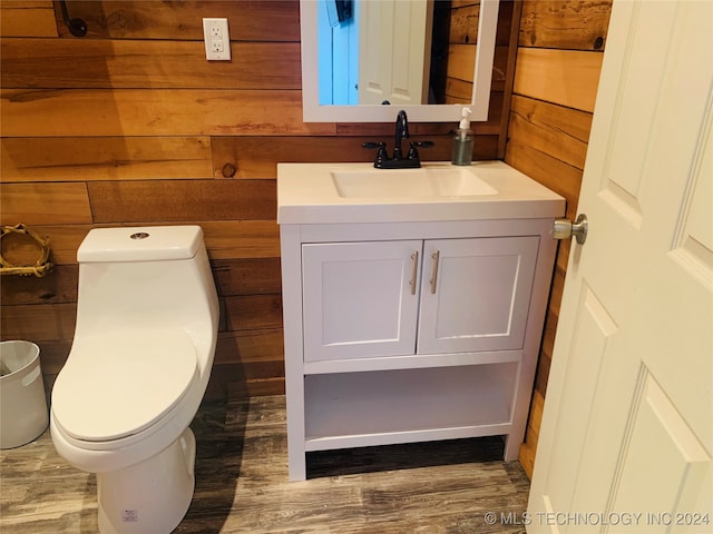 bathroom with wood walls, toilet, vanity, and hardwood / wood-style floors