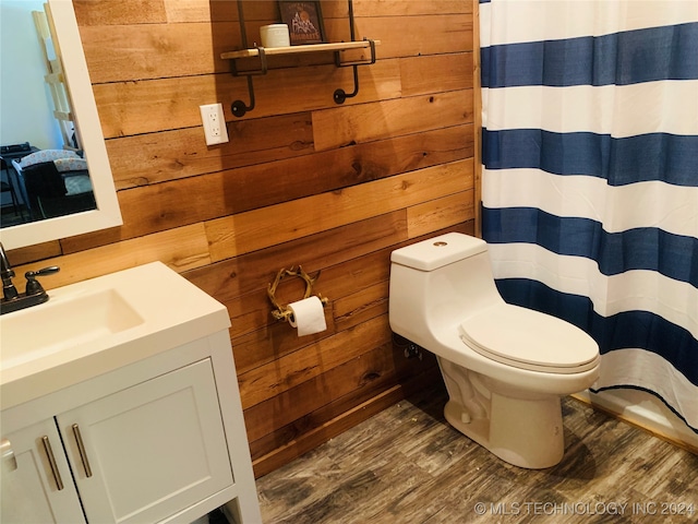 bathroom with wood walls, hardwood / wood-style flooring, vanity, and toilet