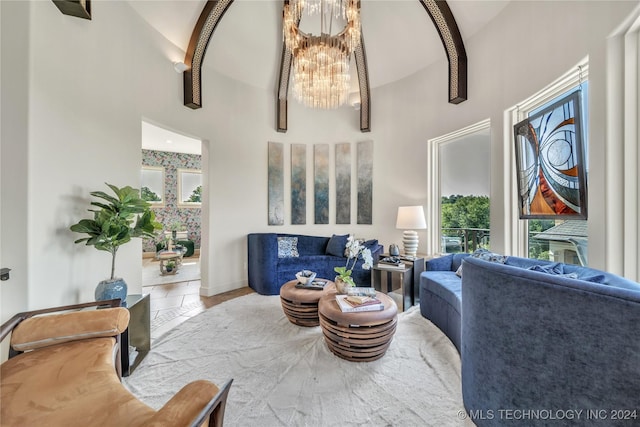 tiled living room with a towering ceiling, an inviting chandelier, plenty of natural light, and baseboards