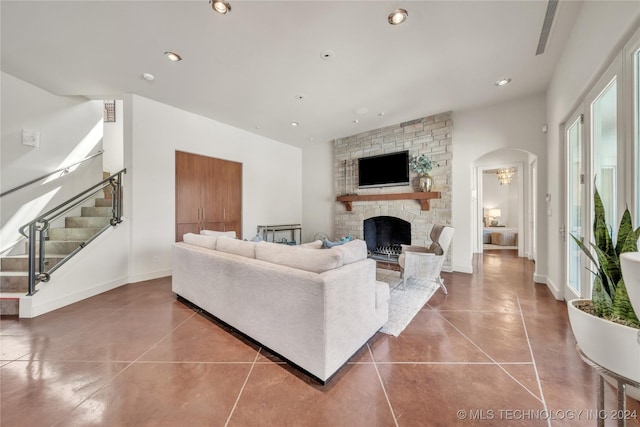 living area featuring baseboards, arched walkways, stairway, a fireplace, and recessed lighting