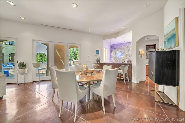 dining room with finished concrete flooring, baseboards, arched walkways, and recessed lighting