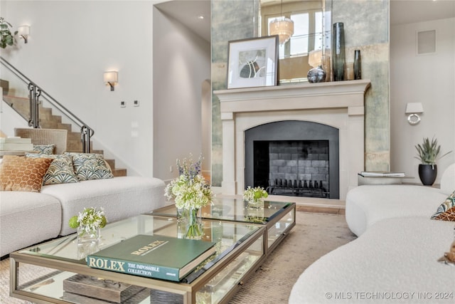 living area with a fireplace with raised hearth, stairway, and visible vents