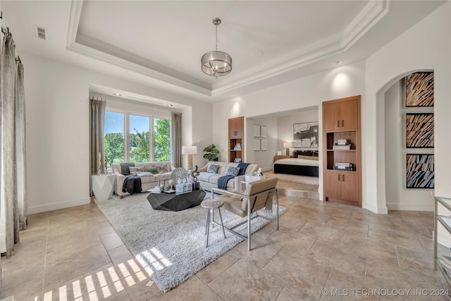 living room featuring a tray ceiling, visible vents, a notable chandelier, and arched walkways