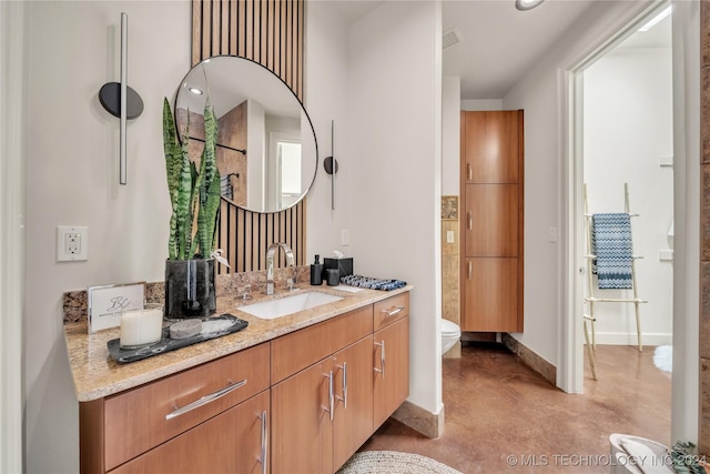 bathroom with toilet, finished concrete floors, baseboards, and vanity