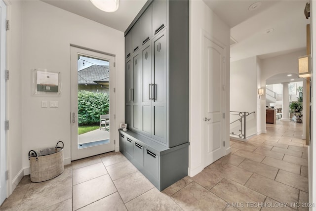 interior space with arched walkways, baseboards, and light tile patterned floors