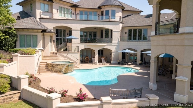 rear view of house with an outdoor pool, a balcony, an in ground hot tub, a patio area, and stucco siding