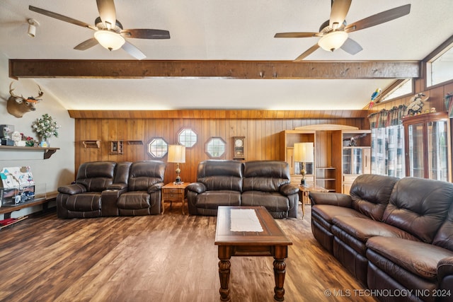 living room with ceiling fan, wood walls, wood-type flooring, and vaulted ceiling with beams