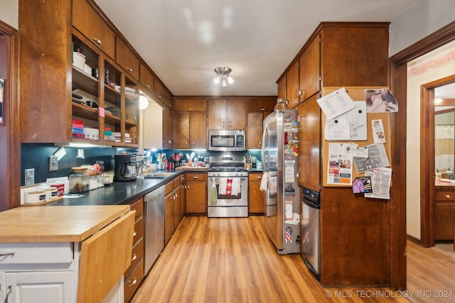 kitchen featuring sink, stainless steel appliances, light hardwood / wood-style flooring, and a textured ceiling