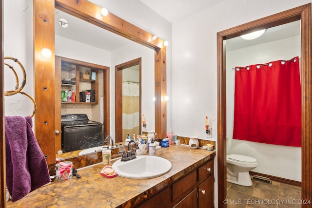 bathroom with washer / clothes dryer, toilet, vanity, and tile patterned flooring