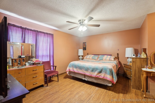 bedroom featuring ceiling fan, hardwood / wood-style flooring, and a textured ceiling