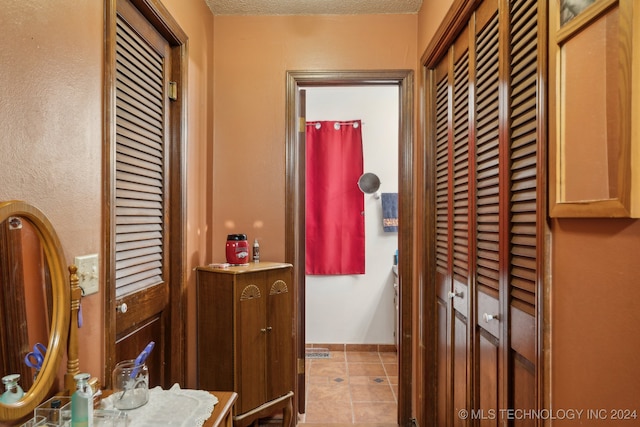 hallway with a textured ceiling and light tile patterned floors