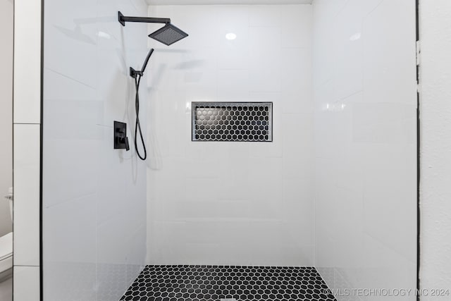 bathroom featuring a tile shower and toilet