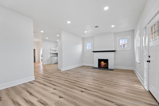 unfurnished living room with light hardwood / wood-style flooring and a brick fireplace