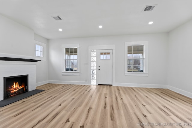 entrance foyer featuring light hardwood / wood-style flooring and a brick fireplace