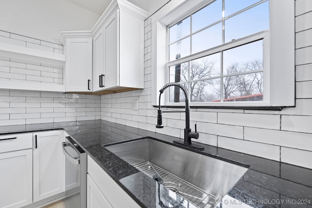 kitchen featuring backsplash, dark stone countertops, white cabinetry, and sink