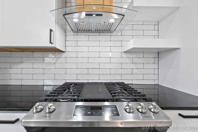 kitchen with island exhaust hood, stainless steel range, white cabinetry, and tasteful backsplash