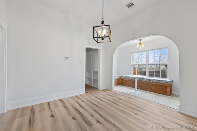 unfurnished dining area featuring light hardwood / wood-style flooring and a chandelier