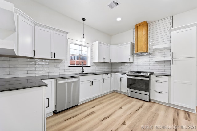 kitchen with pendant lighting, light hardwood / wood-style floors, sink, white cabinets, and appliances with stainless steel finishes