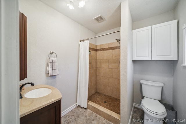 bathroom featuring toilet, vanity, a textured ceiling, and walk in shower