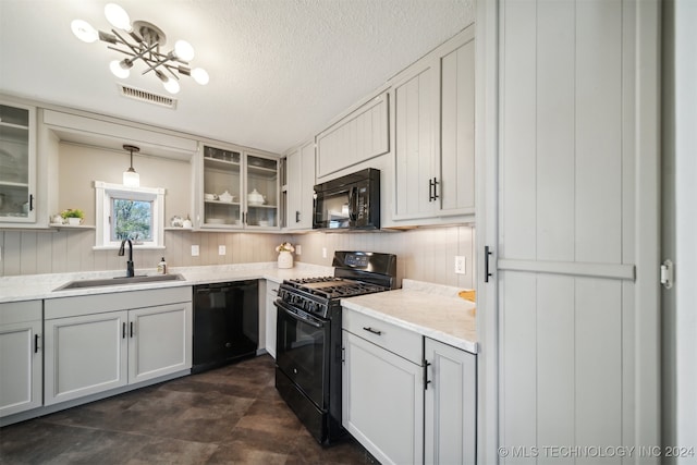 kitchen featuring light stone countertops, sink, hanging light fixtures, a textured ceiling, and black appliances