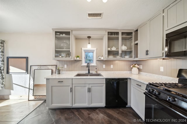 kitchen featuring dark wood-type flooring, sink, black appliances, pendant lighting, and white cabinetry