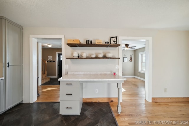 kitchen with hardwood / wood-style floors, a textured ceiling, ceiling fan, and a kitchen breakfast bar