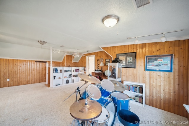 rec room with carpet, track lighting, ceiling fan, and wood walls