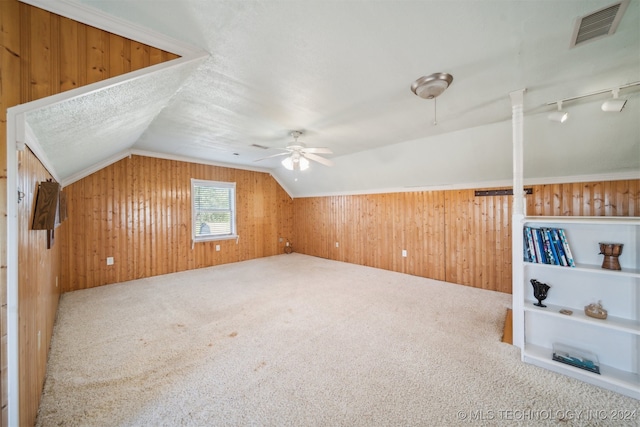 bonus room with ceiling fan, carpet floors, wooden walls, and vaulted ceiling