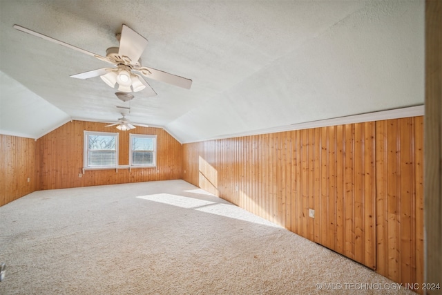 additional living space featuring carpet flooring, wood walls, and vaulted ceiling