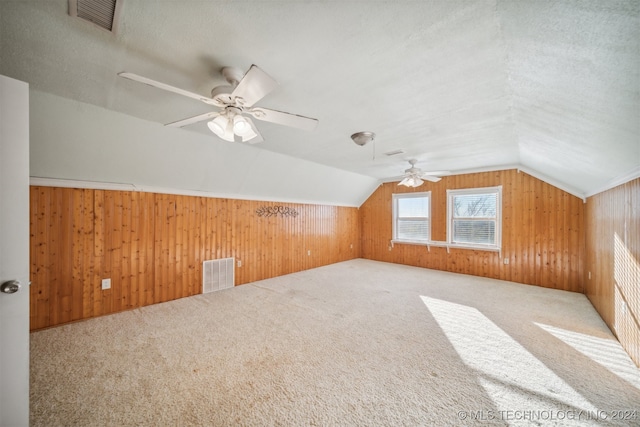 bonus room with ceiling fan, wood walls, carpet floors, and vaulted ceiling