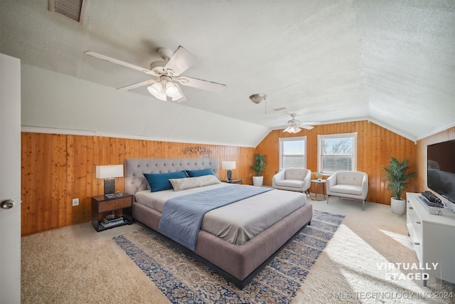 carpeted bedroom featuring ceiling fan, wood walls, lofted ceiling, and a textured ceiling