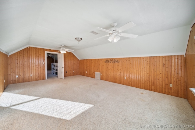 additional living space with carpet, vaulted ceiling, ceiling fan, and wood walls