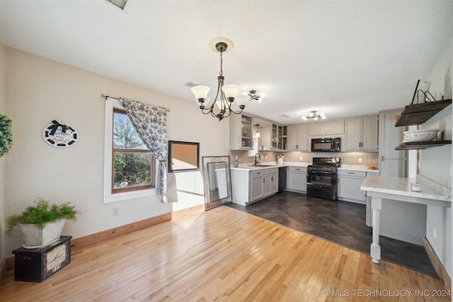 kitchen with dark wood-type flooring, black appliances, decorative light fixtures, and sink