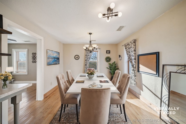 dining room with light hardwood / wood-style floors, an inviting chandelier, and plenty of natural light