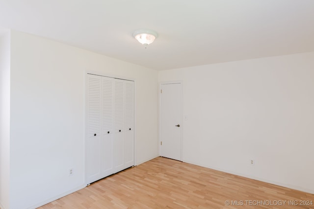 unfurnished bedroom with light hardwood / wood-style flooring and a closet