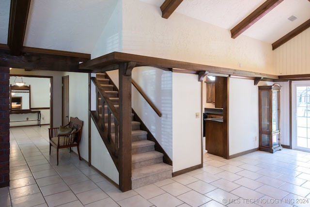 stairway with beamed ceiling, tile patterned floors, and high vaulted ceiling