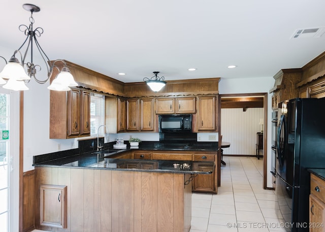 kitchen with pendant lighting, black appliances, sink, a kitchen bar, and a chandelier