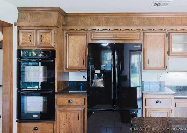 kitchen featuring dark stone countertops, tile patterned flooring, and black appliances