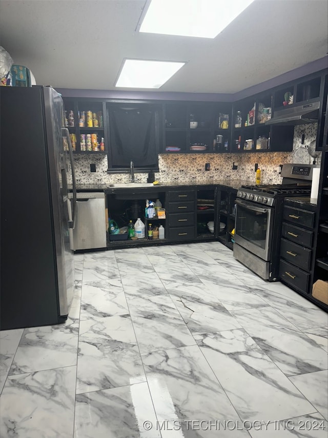 kitchen with stainless steel appliances, a skylight, sink, light tile patterned floors, and decorative backsplash