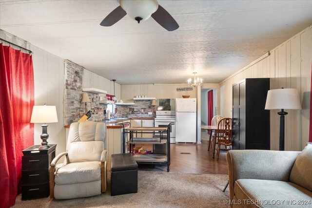 living room featuring wood-type flooring, ceiling fan with notable chandelier, and ornamental molding