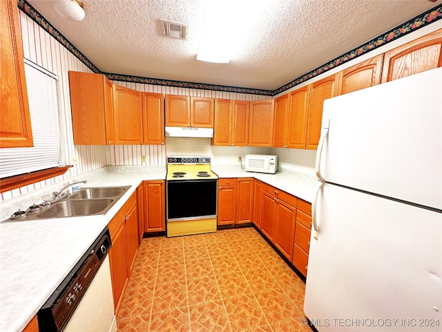 kitchen featuring light tile patterned floors, a textured ceiling, white appliances, and sink