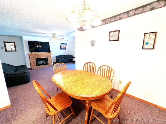 dining room with ceiling fan with notable chandelier, a textured ceiling, carpet flooring, and a brick fireplace