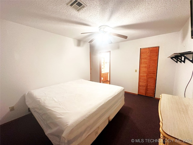 bedroom featuring ceiling fan, a textured ceiling, carpet floors, and a closet