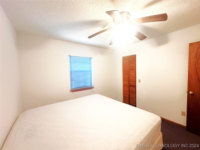 carpeted bedroom with ceiling fan, a textured ceiling, and a closet