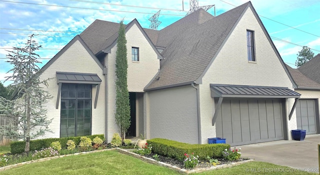 view of home's exterior with brick siding, a shingled roof, concrete driveway, a standing seam roof, and metal roof