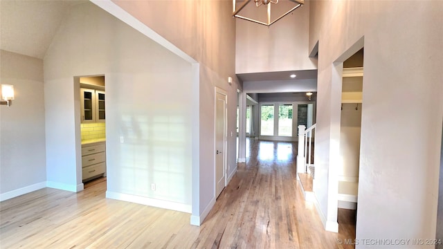 hallway featuring high vaulted ceiling and light hardwood / wood-style flooring