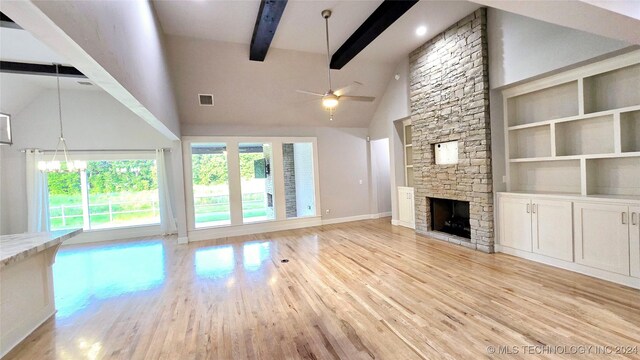 unfurnished living room featuring beamed ceiling, light hardwood / wood-style flooring, a fireplace, and ceiling fan