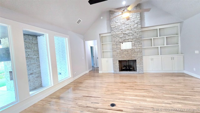 unfurnished living room with ceiling fan, built in shelves, and light hardwood / wood-style flooring